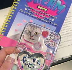 a person holding up a phone case with a cat on it's back and hearts in the middle