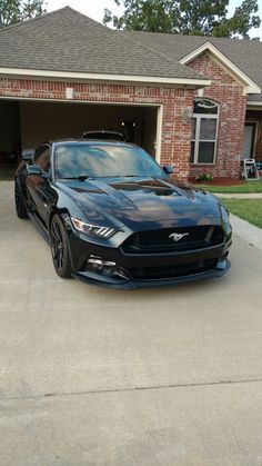 a black mustang parked in front of a garage