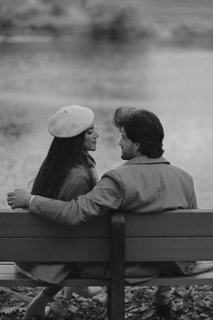 black and white photograph of two people sitting on a park bench looking at each other