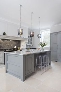 a large kitchen with an island in the middle and three stools at the end