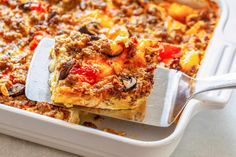 a casserole dish with meat and vegetables being lifted from the casserole