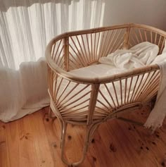 a wicker baby crib in front of a window with white drapes on it