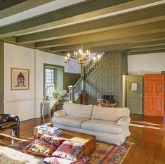 a living room filled with furniture and a chandelier hanging from the ceiling over a wooden floor