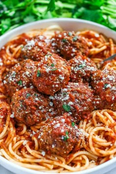 spaghetti and meatballs in a white bowl with parmesan sprinkled on top