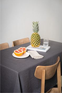 a pineapple sitting on top of a table next to a plate of oranges