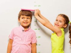 two young children are measuring their height