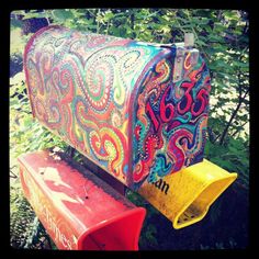 an artisticly painted mailbox sitting in the woods