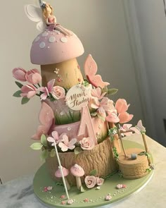 a birthday cake made to look like a mushroom with pink flowers and fairy figurines on top