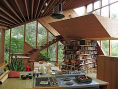 a kitchen with a stove top oven sitting under a wooden ceiling next to a bookshelf