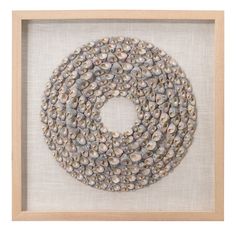 a white frame holding a beaded necklace in the shape of a circle with shells on it