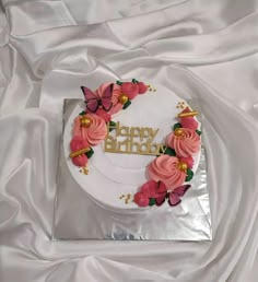 a white birthday cake with pink flowers on it and the words happy birthday written in gold