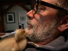 an older man is holding a duckling in his hand