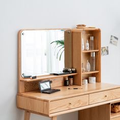 a wooden desk with a mirror on top of it next to a shelf filled with bottles and other items