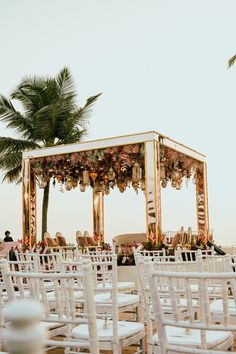 an outdoor wedding setup with white chairs and palm trees