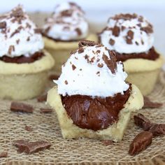 chocolate cupcakes topped with whipped cream and chocolate chips on a burlly cloth