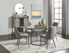 a dining room table with four chairs and a rug on the floor in front of it