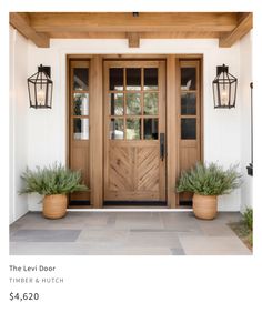 two planters on the front porch of a house with wood doors and windows in them