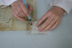 a person with their hands on a piece of paper and a knife in the other hand