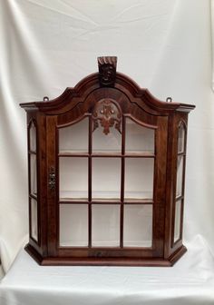 an old fashioned wooden display case with glass doors on the top and bottom shelf,