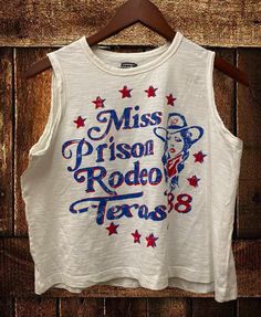 Country Deep Miss Texas Prison Rodeo 1988 Muscle Crop top A feminine version of the muscle crop tank, this womens flowy scoop neck tank top is a must-have style, designed with our exceptionally soft cotton fabrication that softly drapes around curves. The modern armholes and flowy body make it perfect for layering.  Available in Moss color SIZING  Small-body 20 inches wide 18 inches neck to bottom Medium Body-21 inches wide, 19 inches lneck to bottom Large- Body 22 inches wide, 20 inches neck to Retro Tank Vest, Spring Cotton Racerback Muscle Tee, Spring Crew Neck Vest With Graphic Print, Spring Graphic Print Crew Neck Vest, Retro Tank Tops With Letter Print, Summer Scoop Neck Top With Graphic Print, American Retro Graphic Print Summer Tops, Vintage Tank T-shirt For Summer, American Retro Relaxed Fit Cotton Top