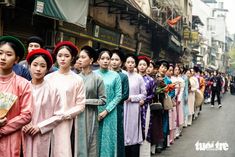 a long line of people standing on the side of a street next to each other