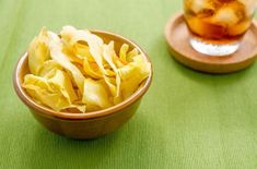 two bowls filled with food sitting on top of a green tablecloth next to a cup