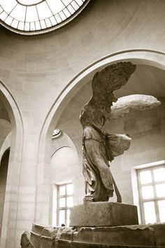 a statue in the middle of a room with a clock on the wall above it