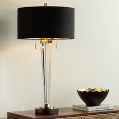 a black lamp sitting on top of a wooden table next to a vase and bowl