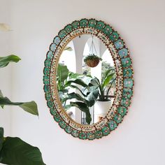 a mirror hanging on the wall next to a potted plant