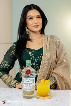 a woman sitting at a table with a bottle of liquor