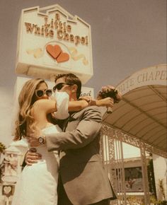 a man and woman are standing in front of a sign for a hotel that says the little white chapel