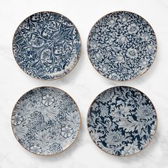 four blue and white plates sitting on top of a marble countertop next to each other