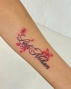 a woman's arm with flowers and the word love written in cursive writing