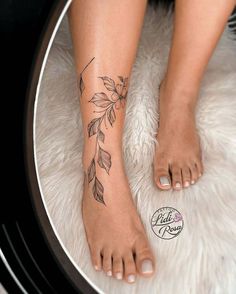 a woman's foot with a flower tattoo on her left leg and the bottom part of her bare feet