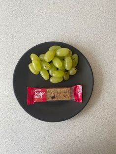 grapes and crackers on a black plate next to a bag of peppermint