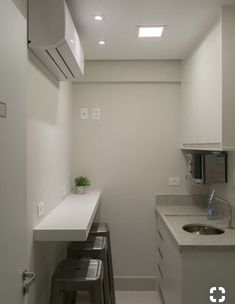 an empty kitchen with white cabinets and counter tops, two stools are in front of the sink