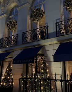 a building with christmas decorations on the balconies and lights in front of it