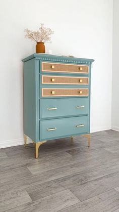 a blue dresser sitting on top of a hard wood floor next to a white wall