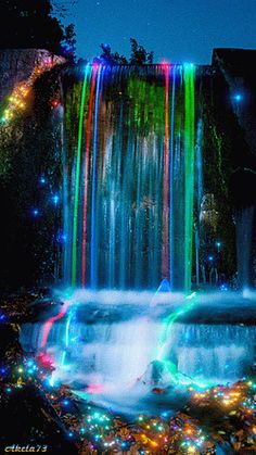 a waterfall with colorful lights on the side and water cascading down it's sides