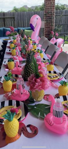 a table set up with pineapples, flamingos and pink flamingo plates