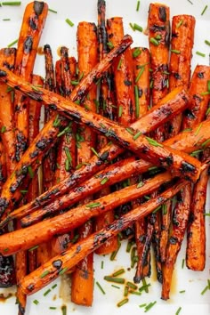 roasted carrots with herbs on a white plate next to a knife and fork, ready to be eaten