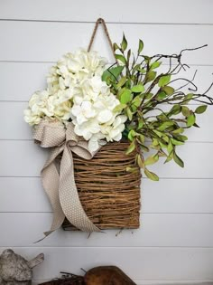 a wicker basket with white flowers hanging on the wall next to a wooden log