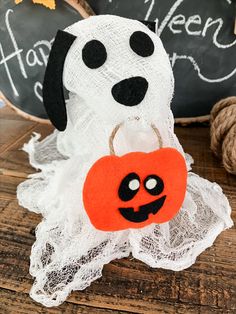 a dog with a pumpkin in its mouth sitting on a table next to a chalkboard