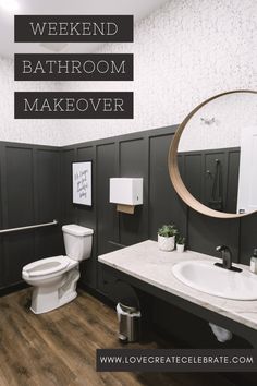 a bathroom with black and white walls, wood flooring and a round mirror over the toilet