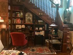 a living room filled with lots of furniture and bookshelves next to a stair case