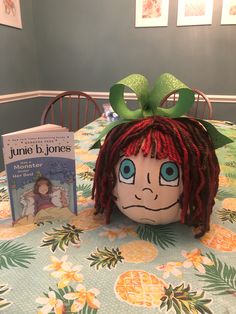 a stuffed doll with red hair and green bow on top of a table next to two children's books