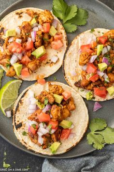 three chicken fajitas on a plate with cilantro and lime