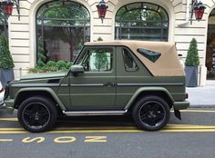 a green jeep parked in front of a building