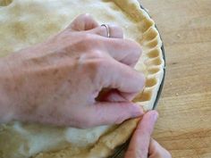 a person is making a pie crust on a wooden table