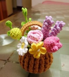 a crocheted basket with flowers in it sitting on the floor next to a tiled floor